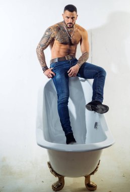 Küvette. Banyo kenarında oturan kaslı gövdeli sakallı İspanyol adam. Vahşi latino adam banyoda rahatlatıcı. Spa banyosu ve jakuzi