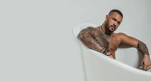 Spa e higiene. tempo para relaxar no banheiro. carisma de confiança. Desportista brutal. esteróides. homem musculoso com corpo atlético. abdominais sexy de tatuagem homem na banheira. Fique limpo e fresco. espaço de cópia — Fotografia de Stock