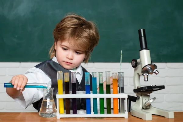 Labb Mikroskop och provrör. Liten Kid vetenskapsman tjänar kemi i skolan Lab. Barn i klassrummet med svart tavla på bakgrunden. Junior år kemi — Stockfoto