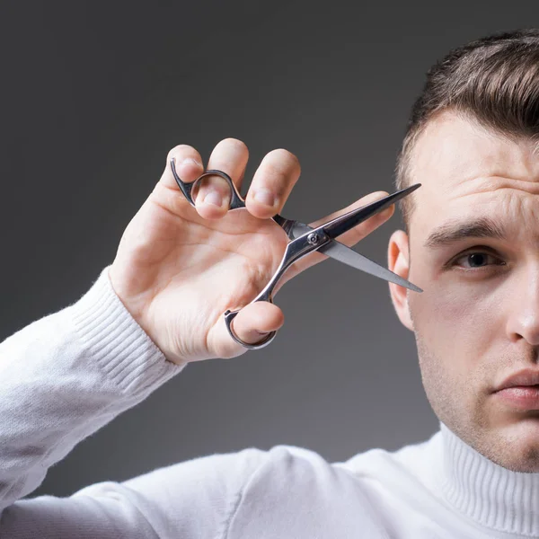 Haar knippen. Een man houdt een schaar vast. Barber glanzende kapsel houden stalen schaar. Creëer je stijl. Macho zelfverzekerde kapper knipte haar. Barbershop service concept. Professionele kapper apparatuur — Stockfoto