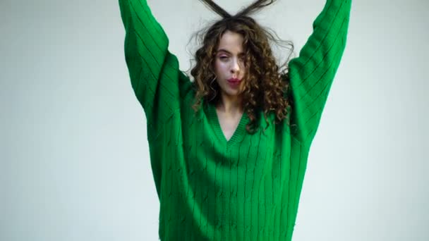 Cheerful beautiful girl with curly hair, braces on her teeth, smiling broadly with her mouth open. Concept fun, happiness, laughter. Fashion woman in green sweater. Parisian woman with long curly hair — Stock Video