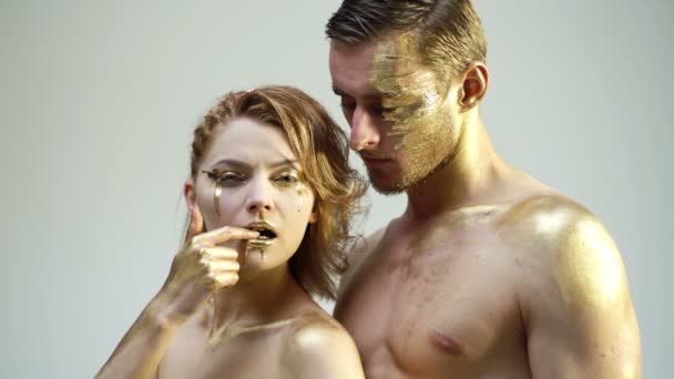 Male and female face around. The womans head lies on the shoulder of a man. All painted in gold paint, the feeling of a single whole organism.Look in the frame. Rich golden makeup. Sexy coulpe. — Stock Video