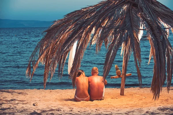 Pareja joven sentada desnuda en la playa — Foto de Stock