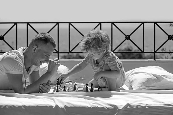 Il bambino gioca a scacchi con il padre. Vacanze estive di famiglia felice. La famiglia viaggia con il bambino il giorno dei padri. padre con figlio sul balcone giocare a scacchi. Amore e fiducia come valori familiari — Foto Stock