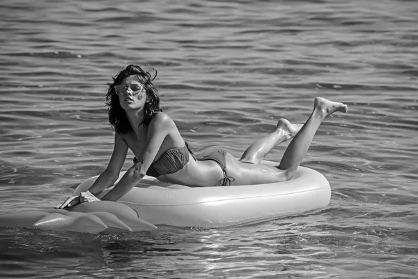 Banhos de sol de sensual jovem nadam no colchão de ar. banhos de sol em mattrees de abacaxi em água do mar . — Fotografia de Stock