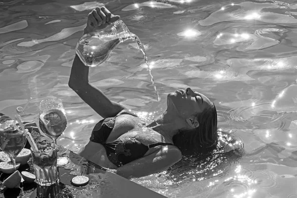 Erfrischung und Schwimmen im Sommerpool. Erfrischung der Frau mit Wasser, Cocktails und Früchten. — Stockfoto