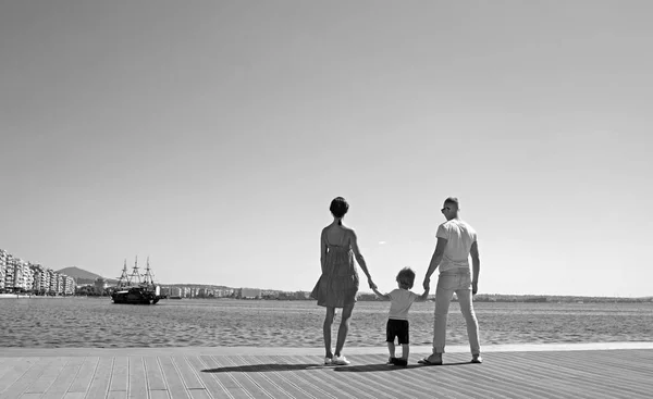 Feliz familia en la playa. La gente mira al futuro en las vacaciones de verano. Padre, madre e hijo contra el fondo azul del mar y del cielo. Concepto de viaje . — Foto de Stock