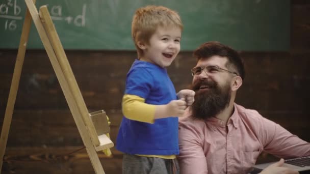 黒板にチョークで描く小さな男の子。幼児教育と遊びの概念学習コンセプト。教育委員会の背景にある学生の机に息子を持つ男。父と息子. — ストック動画
