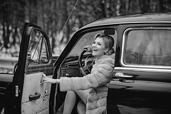 Mode en retro stijl, mannequin in winter bontjas rijdt retro auto. — Stockfoto