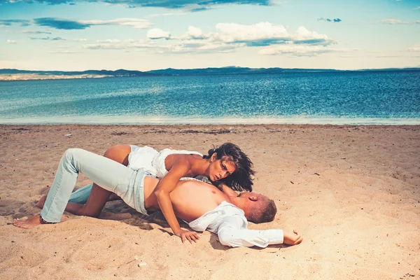 セクシーなボディとの愛のカップルは、砂浜でリラックスします。愛のカップルはビーチでお互いを愛してください。. — ストック写真