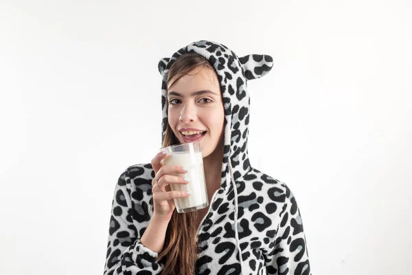 Kanske ett varmt bad och ett glas mjölk. Ung vacker kvinna i fläckig Ko pyjamas håller glas mjölk. Bedårande flicka dricker glas mjölk. Ta ett glas mjölk varm innan du går och sover — Stockfoto