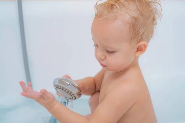 Baby in Badewanne. glückliches Kleinkind, das mit Mutter und Schaum spielt. Baby badet in weißer Badewanne. — Stockfoto