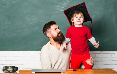 Öğretmen sınıfta masabaşında okuyan öğrencilere yardım ediyor. Kara tahta kopyalama alanı. Okul çocukları. Küçük öğrenciler. Sınıfta ilkokul öğretmeni ve öğrenci