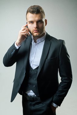 Takım elbiseli adam akıllı telefon kullanıyor. Telefonla çalışan bir iş adamı. Lüks klasik takım elbiseler, moda. Erkek modası. Buluşma telefonu. Ana sorumluluk. Bu günlerde işe yarıyor. Mevcut proje tartışılıyor