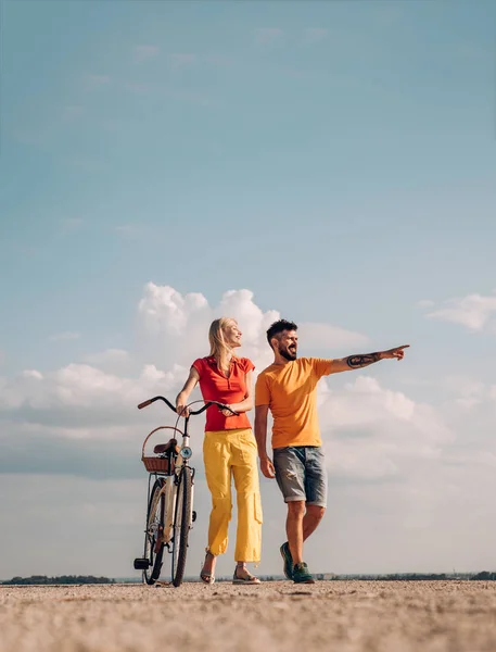 Das Konzept von Liebe und Lebensstil. sexy Frau mit Oldtimer-Fahrrad auf einer Landstraße. Erlebnis- und Ferienkonzept. Lächelndes Paar, das Spaß über dem Himmel hat. — Stockfoto