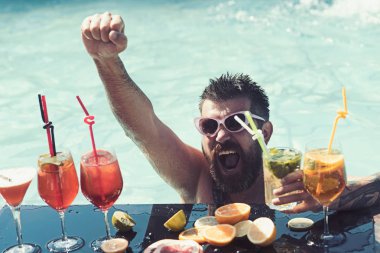 Su havuzunda yüzen adam. Yaz tatili ve parti. Havuzda kokteyl ve sakallı adam.