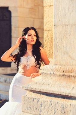 Kadın taş antik sütun yazın. Şık saç ile beyaz elbiseli seksi kız. Şatodaki düğün töreninde gelin kız. Düğün moda ve güzellik salonu. Moda modeli ya da Prenses Giydir