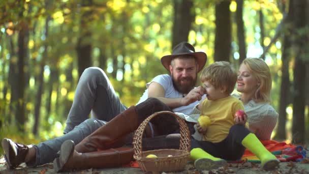 幸せな家族の概念。日没の自然の上に母の父と子供の息子。秋の公園で幸せなアクティブな家族。美しい家族は自然の緑の芝生の上に休む.自由と幸せな家族の概念. — ストック動画
