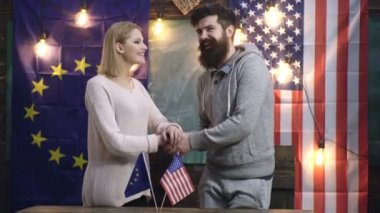 Amerikan eli Amerikan ve Euro bayraklarının arka planında Avrupa'nın elini sallıyor. Amerikan ve Avrupa dostluğu. Amerikan ve Avrupa Birliği bayrakları illüstrasyon üzerinde el sıkışma. Halkların kavram dostluğu.