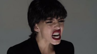 Kırmızı dudaklı güzel kızın portresi bağırıyor. Kızgın bir kadının bağırıp çağırmasının yüzü. Ağzı tamamen açık bağıran kadını kapatın. Kadın çığlıklar ve hareket ler korkmuş ve kızgın gri izole.