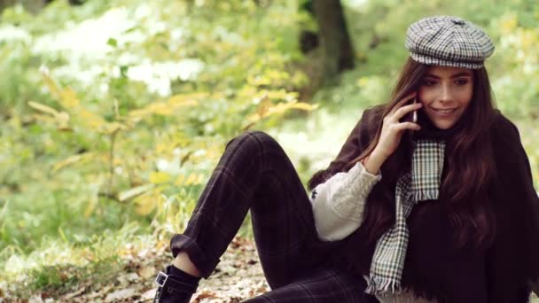 Ragazza felice posa con il telefono. Allegro bella ragazza in maglione all'aperto in bella giornata d'autunno. Ragazza sognante con i capelli lunghi in maglia maglione . — Video Stock