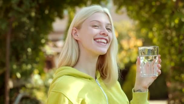 Ritratto di donna con acqua di vetro. Giovane donna che beve acqua. Agita il ritratto della ragazza bionda. Concetto di acqua salubre . — Video Stock