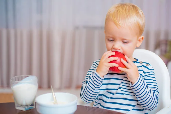 Peuter met snack thuis. Kind eet PAP. Kid cute Boy blauwe ogen zitten aan tafel met plaat en voedsel. Gezonde voeding. Gezonde voeding. Jongen schattig baby eten ontbijt. Baby voeding. Gezond eten — Stockfoto