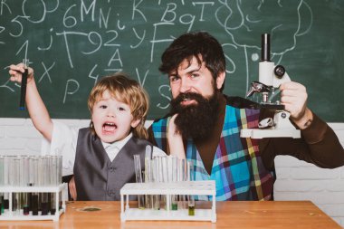 Okula geri dön. İlkokul öğretmeni ve sınıfta öğrenci. Evde eğitim. Baba, okulda ki sınıfta oğluna kimya veya biyoloji öğretiyor. Ilkokul. Mutlu aile.