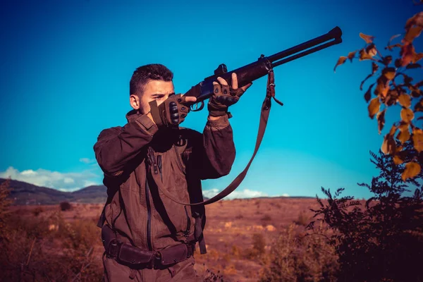 ハントに散弾銃銃を持つハンター。狩猟用ライフルの口径。スコープスポッティング動物と強力なライフルを持つハンター。森の中の密猟者. — ストック写真