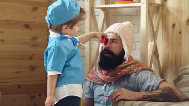 Doctor examinando a un niño en el hospital. Doctor y paciente. Feliz bebé lindo en el examen de salud. Concepto de medicina y salud. Corazón y pulmones. Feliz niño sano es jugado por un médico. Papá e hijo juegan . — Vídeos de Stock