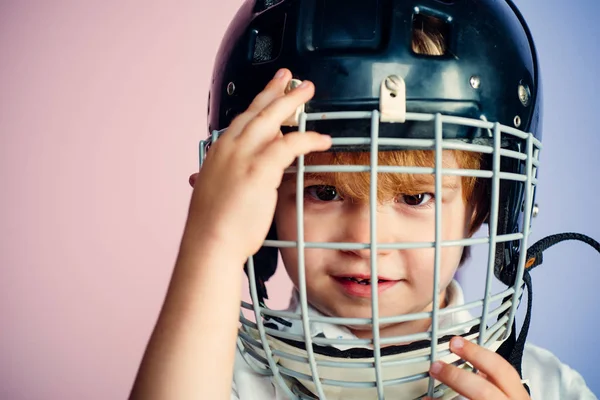 Sport childhood. Future sport star. Sport upbringing and career. Boy cute child wear hockey helmet close up. Safety and protection. Protective grid on face. Sport equipment. Hockey or rugby helmet