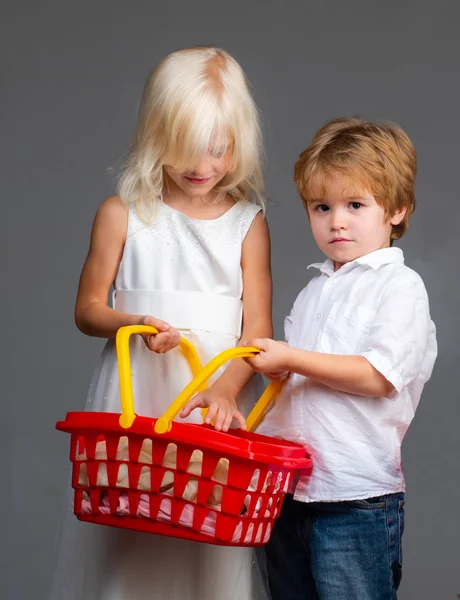 Un paio di bambini tengono un cestino giocattolo di plastica. Shopping al centro commerciale. Acquista con sconto. Acquista prodotti. Gioca a shop game. Carino cliente acquirente cliente tenere carrello della spesa. Ragazza e ragazzo bambini shopping. Negozio per bambini — Foto Stock