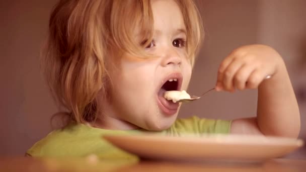 Happy child. Cheerful baby child eats food itself with spoon. Happy baby boy spoon eats itself. Little baby are eating. Baby eating. — Stock Video