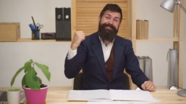 Yaşasın. Açık ağız çığlık ile neşeli keyifli yakışıklı Portresi memnun hayretle hayretle freelancer masada oturan ellerini kaldırarak. O zaferi savuruyor. Harika bir iş.
