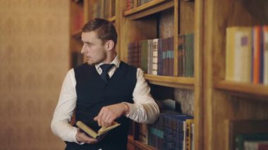 Erkek gazeteci raflarda duran makale için araştırma yapan kitap okudu. Zeki yazar kitap tutuyor ve bilgiyi analiz ediyor. Takım elbiseli adam halk kütüphanesinde akşam vakti geçiriyor.