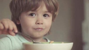 Gülme sevimli çocuk erkek bebek mama sandalyede oturan ve mutfak arka planda yemek. Mutlu çocuk. Evde kahvaltı yiyen sevimli bir çocuk. Aç küçük çocuk yiyor. Mutfakta bebek yeme yemeği.