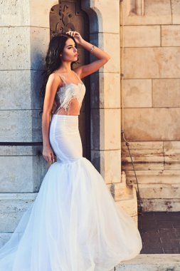 Şık saç ile beyaz elbiseli seksi kız. Kadın taş antik sütun yazın. Düğün moda ve güzellik salonu. Şatodaki düğün töreninde gelin kız. Moda modeli ya da Prenses Giydir