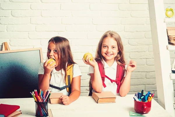 Kleine meisjes eet appel bij de lunchpauze. Terug naar school en huis het scholen. Vriendschap van kleine zusters in de klas op de dag van de kennis. De schooltijd van meisjes. Gelukkig schoolkinderen op les in september 1 — Stockfoto