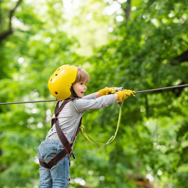 High ropes walk. Child. Kid climbing trees in park. Eco Resort Activities. Hike and kids concept. Helmet and safety equipment