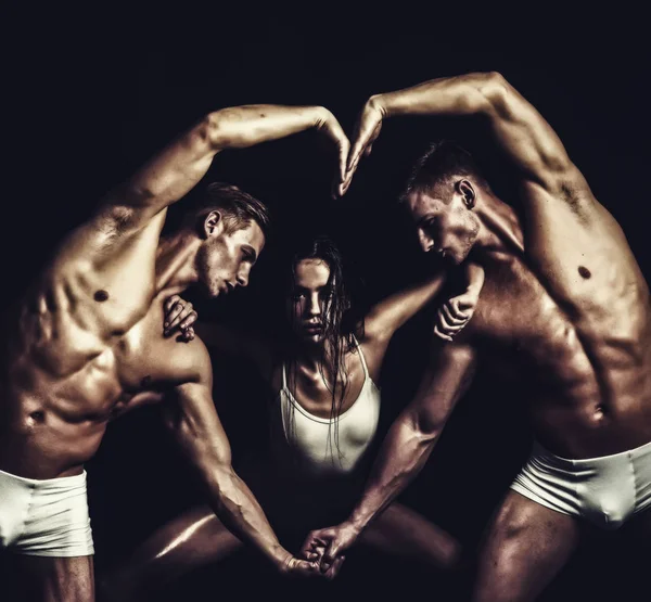 Ginnasti di circo a pilates o formazione di yoga. Gemelli uomini con corpo muscoloso e ragazza. Scuola di ginnastica ed energia. Fitness e dieta. concetto di San Valentino. forma del corpo del cuore delle persone sportive — Foto Stock