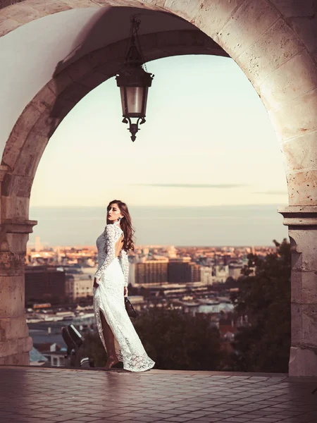 Schoonheid vrouw in witte jurk op uitzicht op de stad. Schoonheid model met lange haren op balkon — Stockfoto