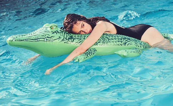 Entspannen Sie sich im luxuriösen Schwimmbad. Mode Krokodilleder und Mädchen im Wasser. Sommerurlaub und Reisen auf die Malediven. Abenteuer von Mädchen auf Krokodil. Frau auf See mit aufblasbarer Matratze — Stockfoto