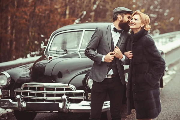 Viagem e viagem de negócios ou engate caminhadas. Retro coleta de carro e reparação de automóveis por motorista mecânico. Escolta de rapariga pela segurança. Casal apaixonado no encontro romântico. Homem barbudo e mulher sexy no casaco de peles . — Fotografia de Stock