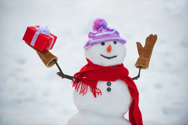 戴着围巾和帽子的雪人。可爱的雪人站在冬天的圣诞景观。有趣的雪人穿着时尚的帽子和围巾在雪场上。问候雪人. — 图库照片