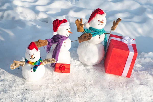 Funny snowmen family. Happy winter snowman family. Mother snow-woman, father snow-man and kid wishes merry Christmas and Happy New Year.