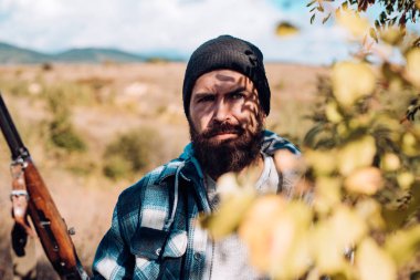 Ormanda kaçak avcı. Avcı avda av tüfeği tabancası ile. Sakallı avcı adam silah tutan ve ormanda yürüyüş.
