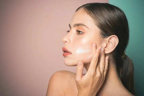 Mantenga la piel hidratada crema hidratante regularmente. Cuidando bien su piel. Hermosa mujer esparciendo crema en su cara. Crema para la piel. Cuidado facial para la mujer. Concepto de piel sana fresca —  Fotos de Stock