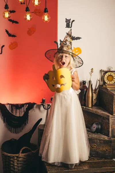 Boldog lány boszorkány Halloween jelmez kalapban állt, és mosolyogva fehér háttérrel. Boldog nevetve gyerek jelmez Halloween. Ajándékok a Halloween-hagyományok a különböző országok. — Stock Fotó