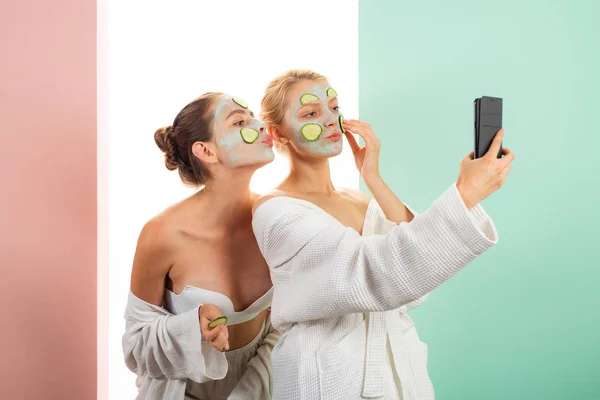 Taking selfie. Anti age care. Skin care for all ages. Women having fun skin mask. Pure beauty. Beauty product. Spa and beauty care. Girls friends sisters in bathrobes making clay facial mask