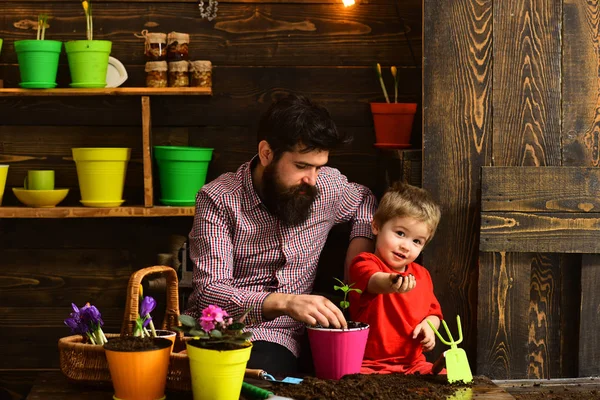 bearded man and little boy child love nature. Flower care watering. Soil fertilizers. Family day. Greenhouse. happy gardeners with spring flowers. Father and son. he loves his job